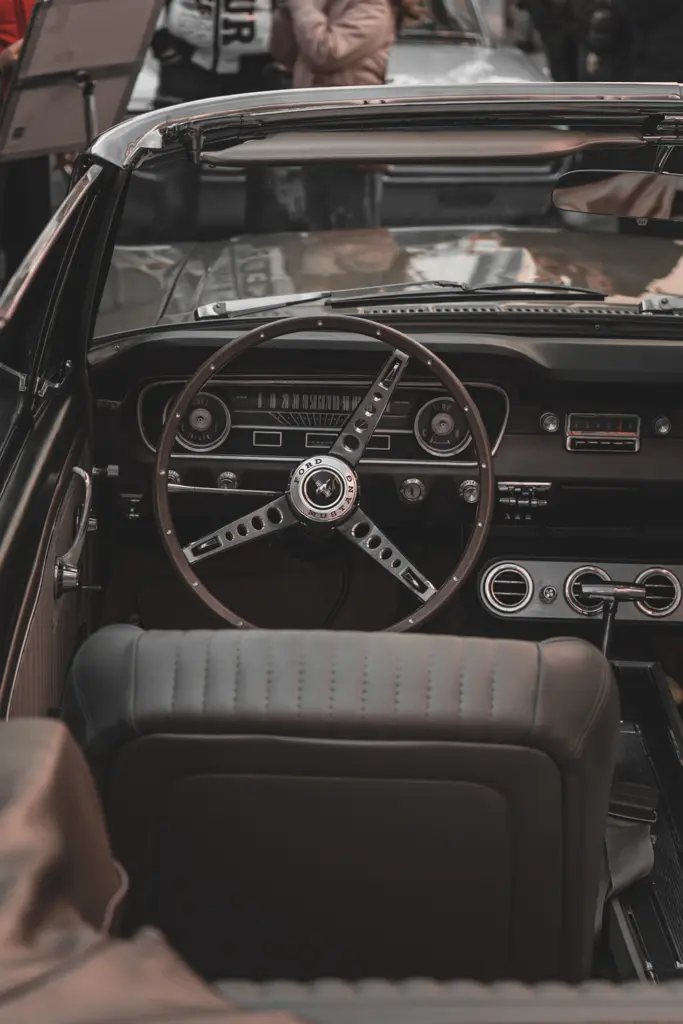 Pohled do interiéru historického kabrioletu Ford Mustang s volantem, palubní deskou a předními sedačkami.