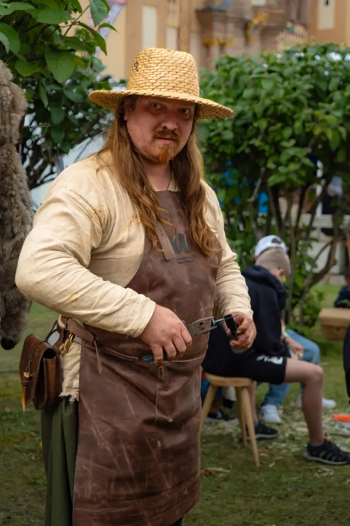 Portrét kováře v kožené zástěře v dílně.