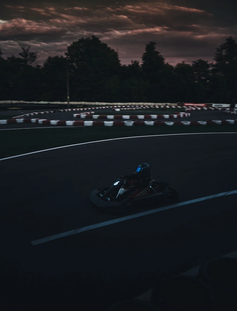 Motokára jede po závodním okruhu pod dramatickou tmavou oblohou při večerní jízdě.